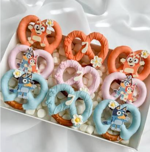 Bluey themed chocolate covered pretzels with blue and white drizzle on a display